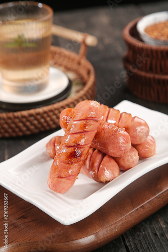 Grilled Sliced Sausages on White Plate with Tea Setting
