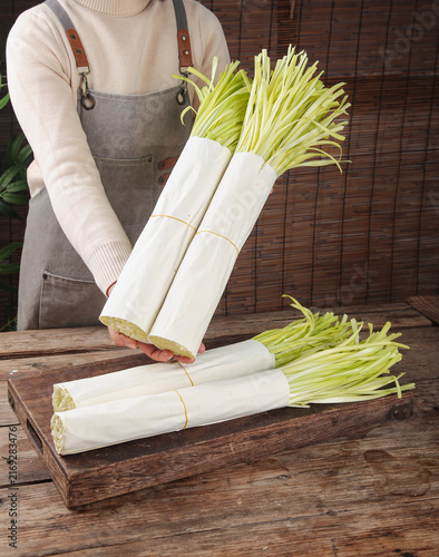 Foto Fresh Green Onions Scallions Bundles on Wooden Board - Organic Vegetables Kitche