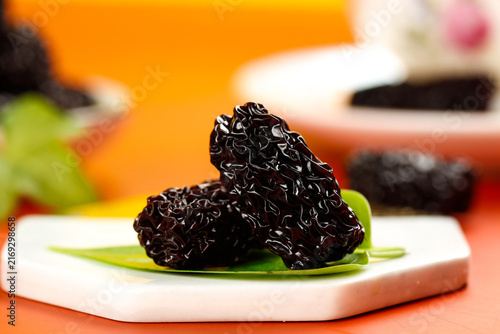 Quadro su tela Black Dried Jujubes from Xinjiang China on White Plate - Traditional Healthy Sna