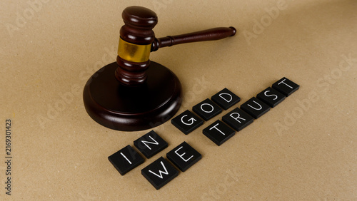 Foto Wooden judge's gavel next to black letter tiles spelling In God We Trust on a li
