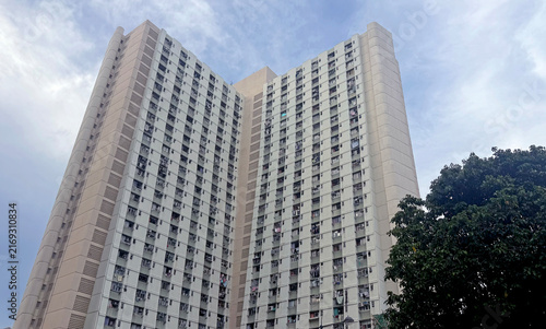 Towering residential building with many windows against a cloudy sky