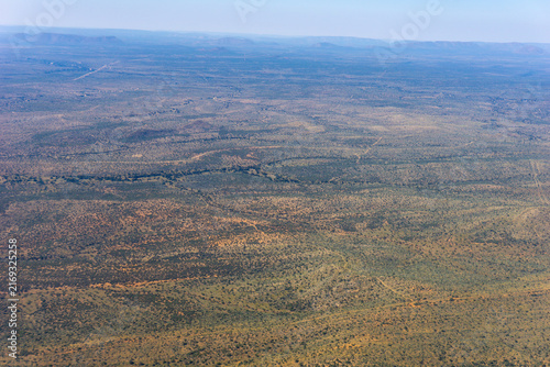 Aerial image Namibia with dirt roads, scattered green acacia bushes, expansive landscape  while flying over the country.