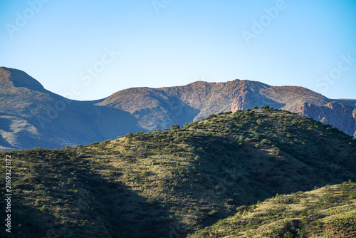 Image of rugged scattered acacia treed hills in aerial image flying over African terrain