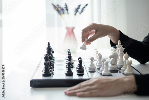 Fotografie Hand of businesswoman moving white king chess piece on chessboard for business s