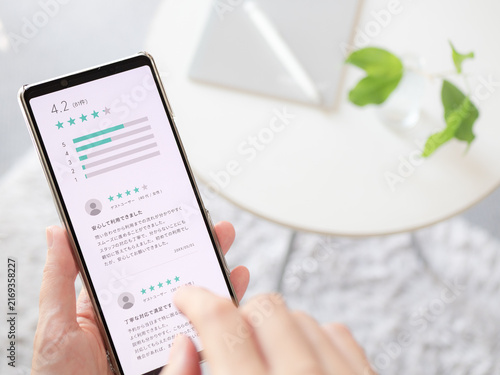 利用サービスの口コミや商品レビューをチェックする女性の手元写真（スマホ画面はオリジナル制作）