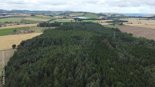 Aerial View Flying Over Small Woodland Surrounded by Countryside
