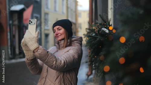 Woman taking selfie in a winter street with decorations in a small town