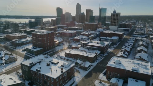Aerial view of a snow-covered city skyline with residential buildings and a distant body of water.