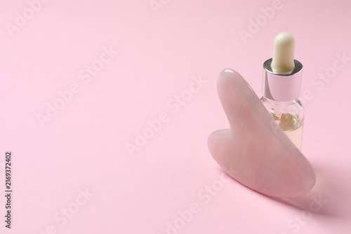 Fotografía Gua sha massager and cosmetic oil on pink background