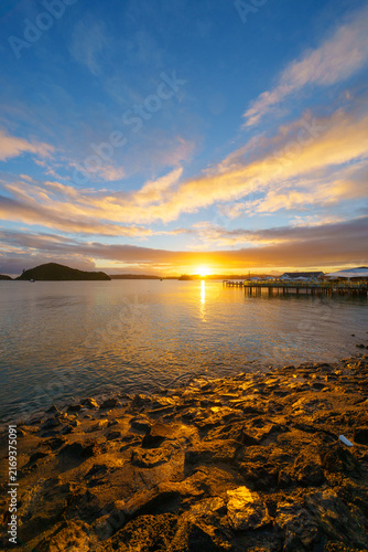 Paihia waterfront at sunrise with suns golden glow on distant horizon