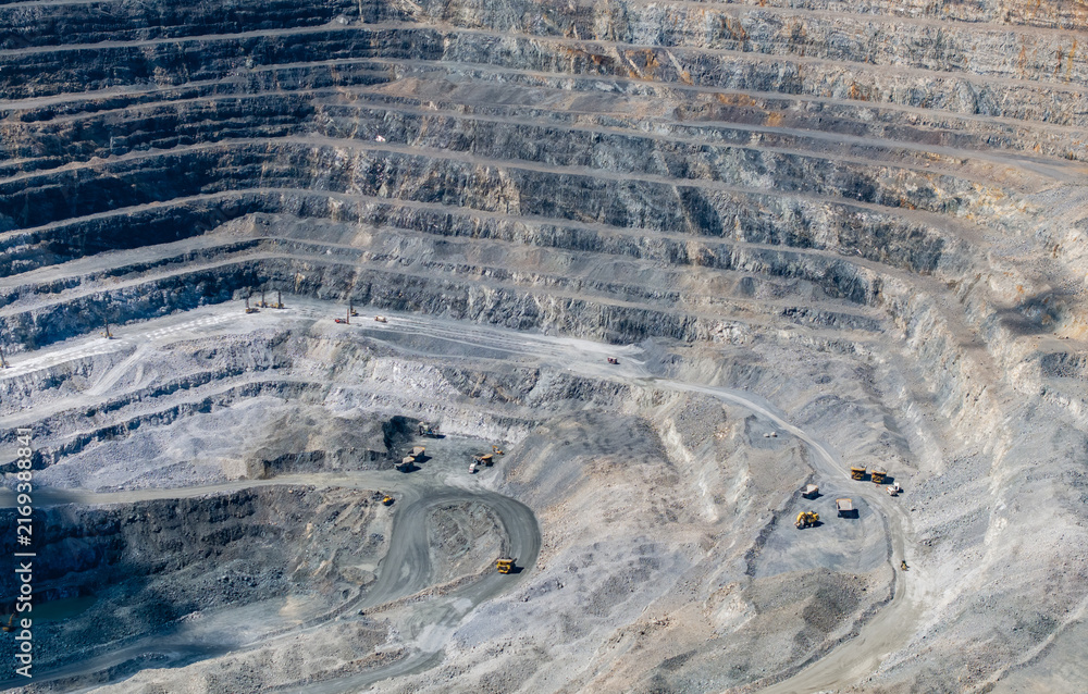 Fototapeta premium Haul trucks operating on terraced benches inside mine pit, industry diamond mining factory