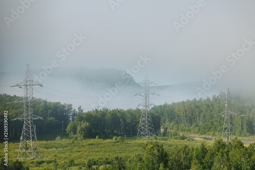 Canvas Print Series of Industrial high voltage towers across foggy green valley