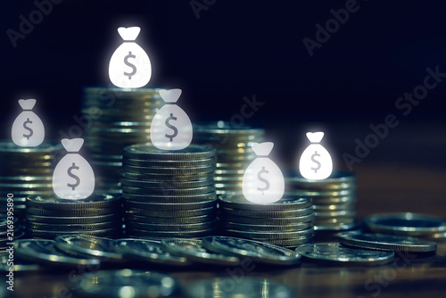 Coin stacks with glowing money bag icons represent savings, wealth, investment funds, financial planning, income growth, capital accumulation, and personal finance management concepts.