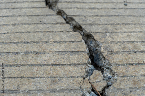 Photography Close-up of deep structural crack on grooved concrete road pavement in horizontal view