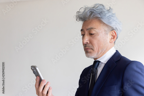 Obraz w ramie スマートフォンの画面が見えにくい老眼のシニアビジネスマン 