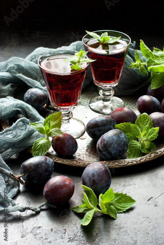 Plum wine or liquor on dark  background and ripe juicy plums