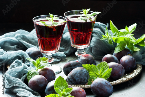 Plum wine or liquor on dark  background and ripe juicy plums
