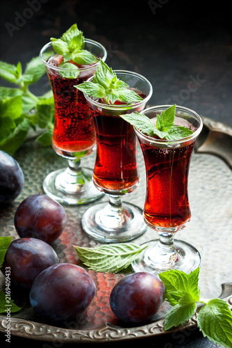 Plum wine or liquor on dark  background and ripe juicy plums