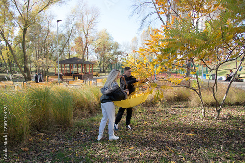 Foto Happy couple enjoying a sunny autumn day in the park, collecting yellow leaves b
