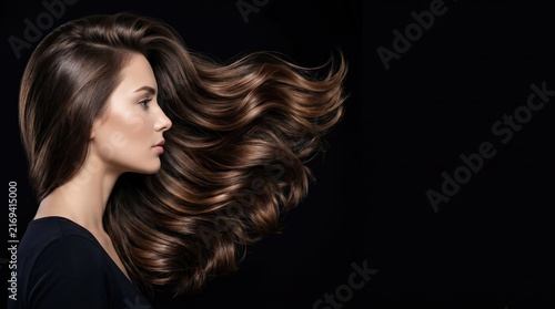 Beautiful woman with long flowing wavy brown hair on a dark