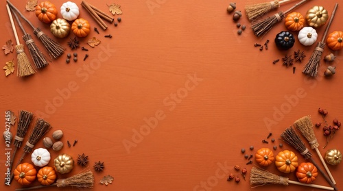 Autumn harvest frame with miniature pumpkins and rustic witch brooms on flat lay orange wooden background for fall seasonal greetings