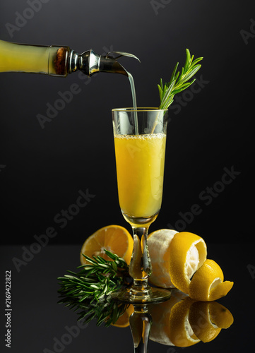 Фотография Traditional Italian liqueur Limoncello with rosemary twig on a black reflective background