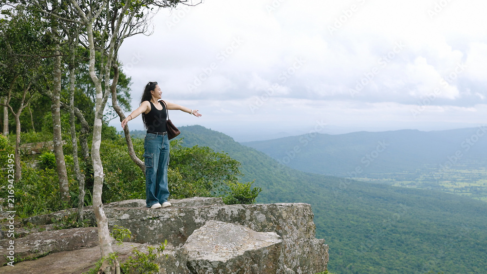 Obraz premium Free Woman Spreading Arms on Cliff Edge Overlooking Mountain Valley