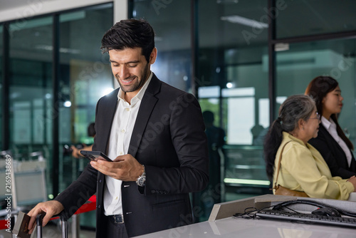 Caucasian businessman is using smart mobile phone while waiting in airline business departure lounge waiting for boarding to airplane