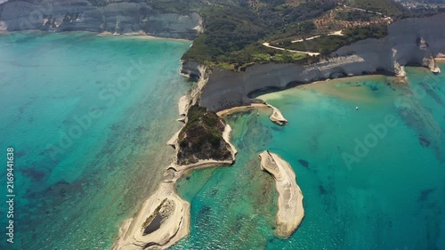 Aerial drone perspective over turquoise sea waters and white sedimentary cliffs of Corfu island Greece.