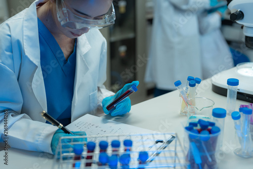 Obraz na plátně Biomedical scientists analyze chemical samples a microscope, advancing vaccine development, biotechnology, medical research, disease prevention, and healthcare innovation