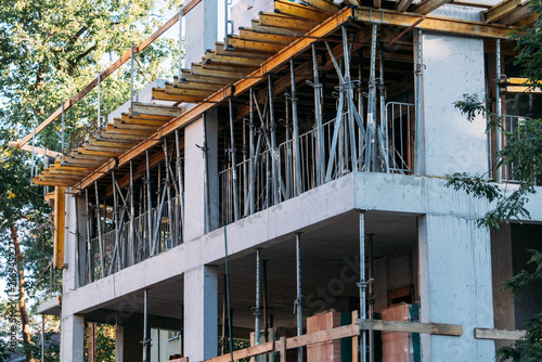 Concrete building under construction with timber formwork and steel props supporting slab. concrete slab formwork, telescopic shoring props, timber beam formwork system