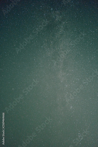 Wide view of clear night sky filled with countless tiny white stars over deep blue to teal gradient background, gentle brightness variation creates calm celestial atmosphere and quiet sense of vast