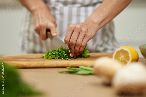 Hands chopping fresh parsley on a wooden board