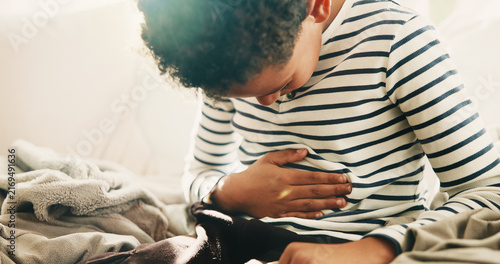 Foto Sick, child and discomfort in home with stomach ache, indigestion or constipation from medical issue