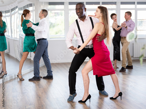 Fotografie Woman with African man participants of dance workshop perform figure waltz