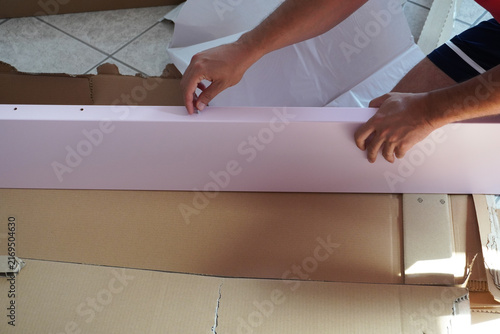 Assembling a pink children's bed. Male hands while assembling a pink children's bed at home. Assembling furniture at home, using tools. Furniture repair and assembly. DIY concept with detailed view of
