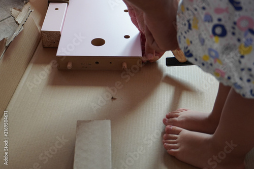 Father assembling a pink children's bed with his small daughter. Furniture parts. Assembling furniture at home. Furniture assembly. DIY concept with detailed view of furniture installation process. 