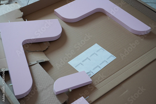 Assembling a pink children's bed. Furniture parts. Assembling furniture at home, using tools. Furniture repair and assembly. DIY concept with detailed view of furniture installation process. 