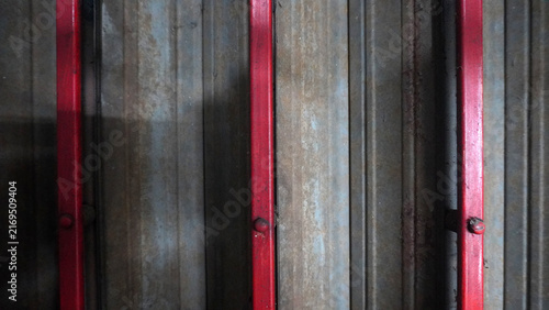 Corrugated metal panel with red vertical beams, industrial texture background with rust details.