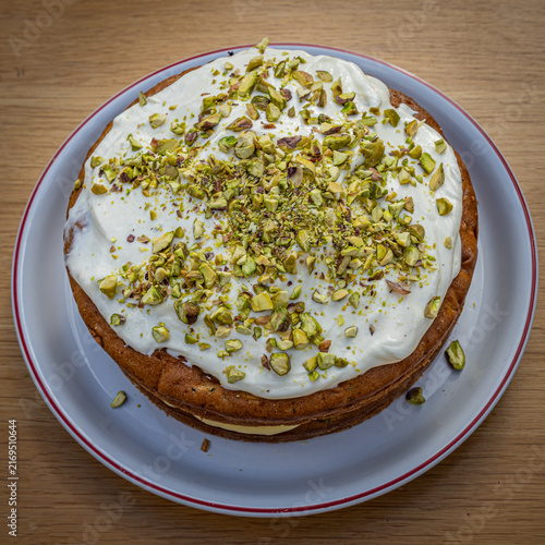 A high angle view of a freshly baked, pistachio topped sponge cake