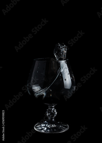 Water splashes inside a clear glass on a black background during a quiet moment