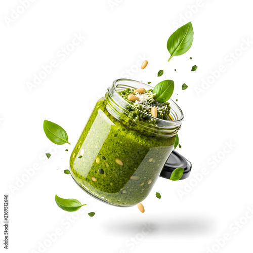 Fresh Pesto in a Jar: A vibrant glass jar of homemade pesto, brimming with basil leaves, pine nuts, and parmesan cheese, floats mid-air, creating an appetizing and dynamic culinary display.