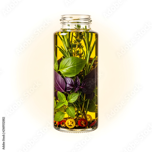 Herbal Infusion in Oil: A clear glass bottle filled with golden olive oil and fresh herbs like basil, rosemary, and mint, with small red peppers visible, creating a vibrant culinary infusion.