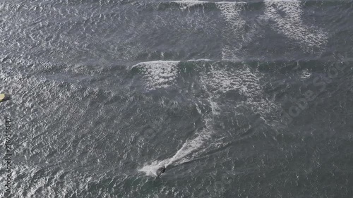 Aerial drone view of kite surfers riding the waves at My Hoa Beach in Vinh Hai, Khanh Hoa, Vietnam, showcasing a spectacular coastal landscape under bright sunlight.
