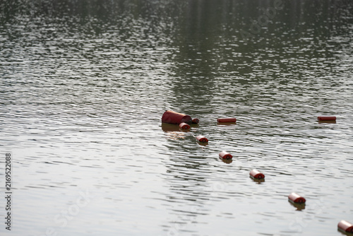 A moody and atmospheric view of red safety buoys representing a strict boundary line in territorial waters. Conceptual imagery of a political crisis, national security hazard, and restricted area 