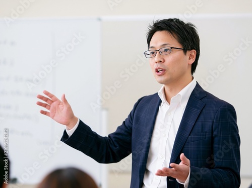 セミナーの会場でホワイトボードを背に熱く語りかける男性講師