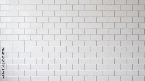 A clean wall featuring glossy white rectangular subway ceramic tiles arranged in a staggered brick pattern.