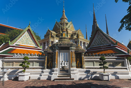 Canvastavla Ornate Crowned Gateway and Multi-Tiered Temple Roofs of Wat Pho Under Clear Blue