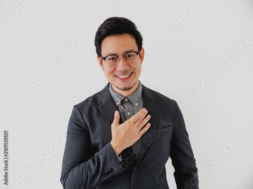 Confident Asian professional man in a suit jacket smiling sincerely with hand over heart.