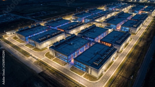 Aerial night view of illuminated modern data center server farm facility with glowing blue and red lights